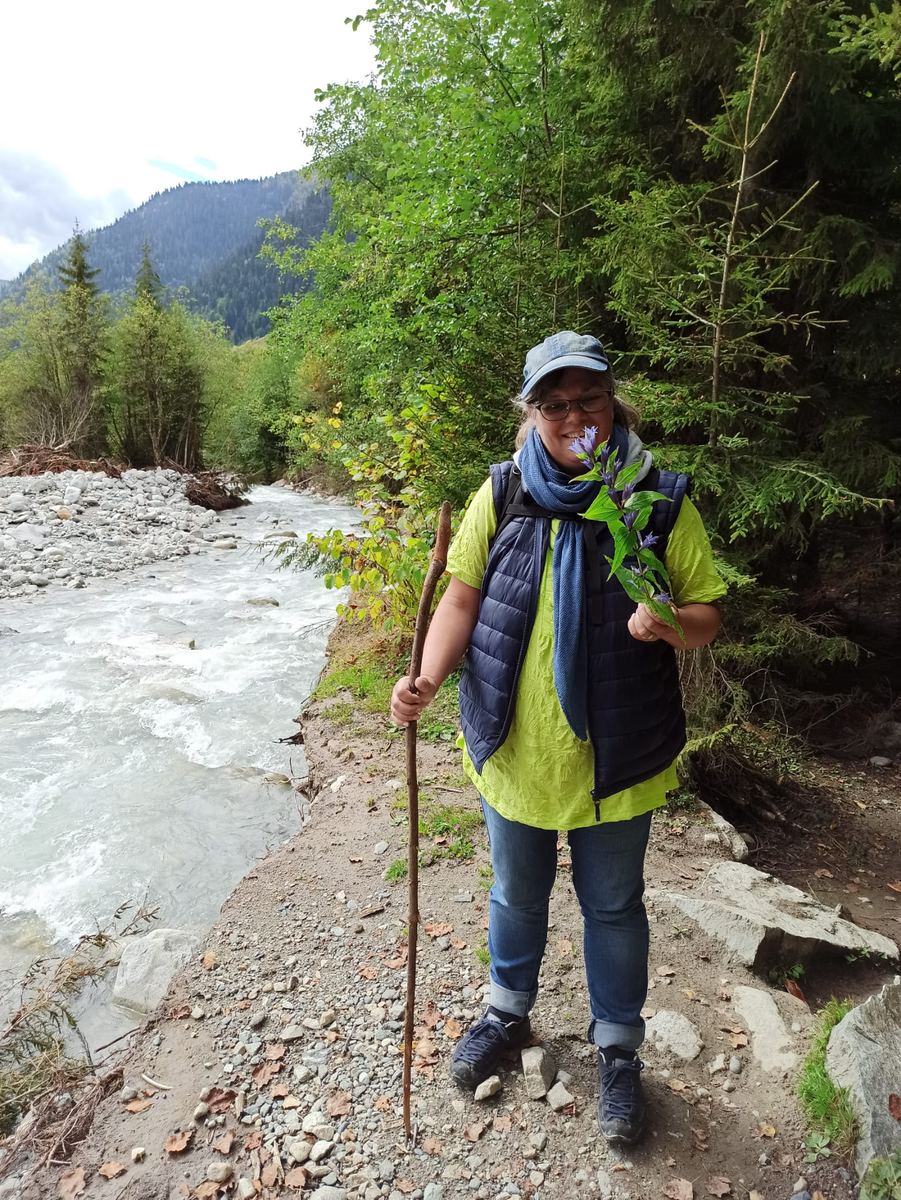 Andrea Marohn mit Wanderstab an einem reißenden Gebirgsfluss in Georgien