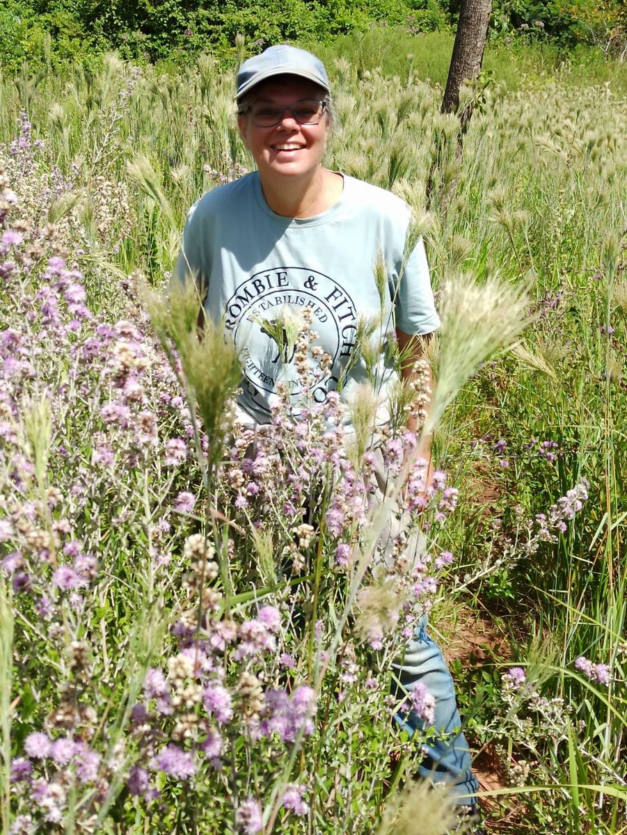 Andrea Marohn lacht mitten in einer Wiese mit lila Blüten