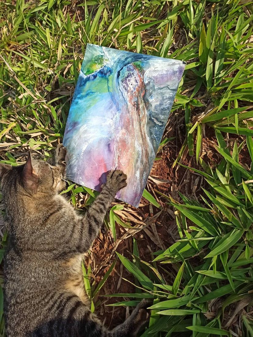 Eine Katze hält ein Aquarell mit beiden Pfoten fest